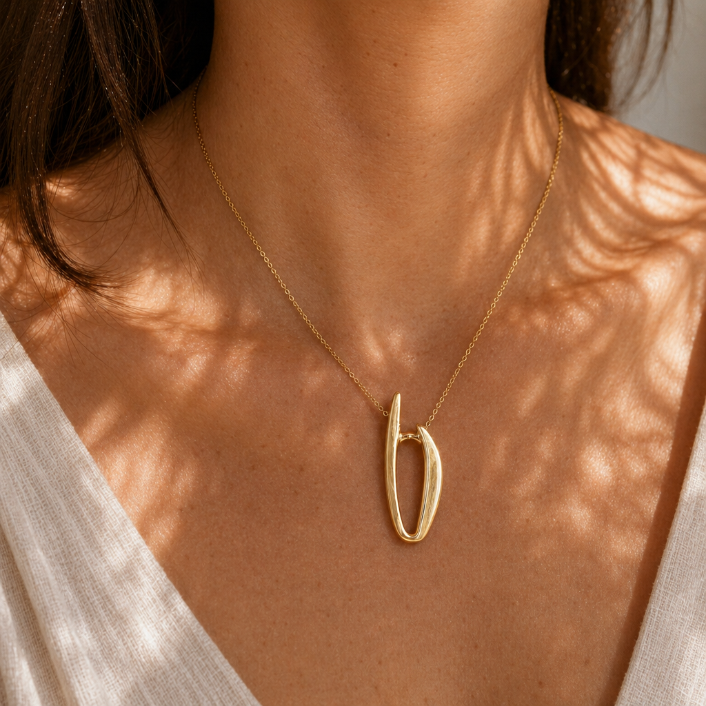 A gold pendant necklace worn on the body to show scale, comfort, and real-life wearability.